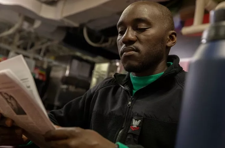 Logistics Specialist 2nd Class Rismas Muhumuza, assigned to supply department aboard the world's largest aircraft carrier, USS Gerald R. Ford (CVN 78), reads a newspaper in the galley, March 16, 2025.